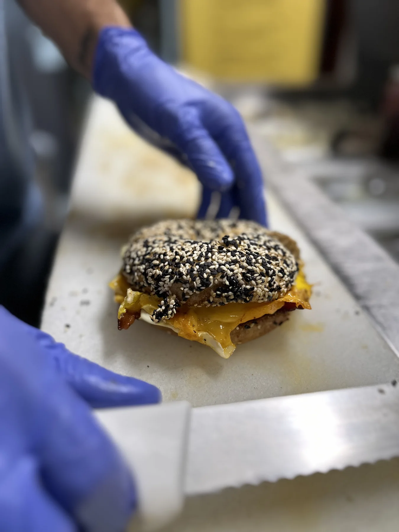 A Bagel Boy team member finishing a freshly made breakfast sandwich
